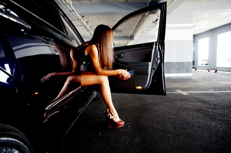 Обнаженная девочка на капоте черного автомобиля