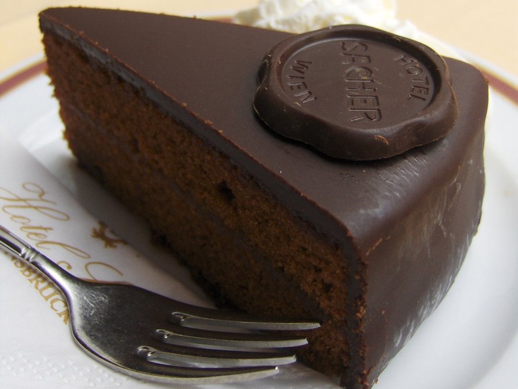 Побалуйте себя тортом «Захер» — плотным шоколадным тортом с насыщенным вкусом — в Вене, Австрия. Город славится своими элегантными и историческими кондитерскими, такими как Cafe Landtmann. блюдо, еда, кухня, путешествие