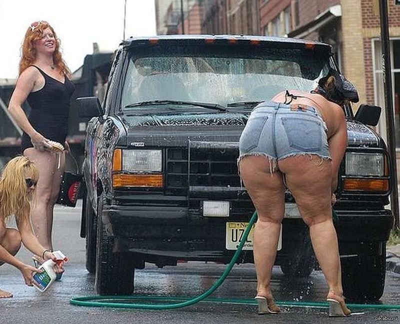 Женщина с обнаженными ягодицами моет машину