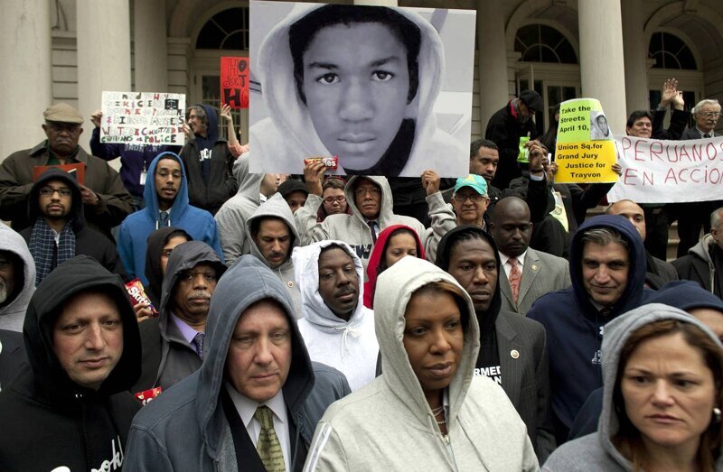Американцы вместе с членами городского совета Нью-Йорка призывают к справедливости после убийства 17-летнего афроамериканского подростка Трэйвона Мартина в марте 2012 года. Парня застрелил белый патрульный-доброволец Джордж Циммерман