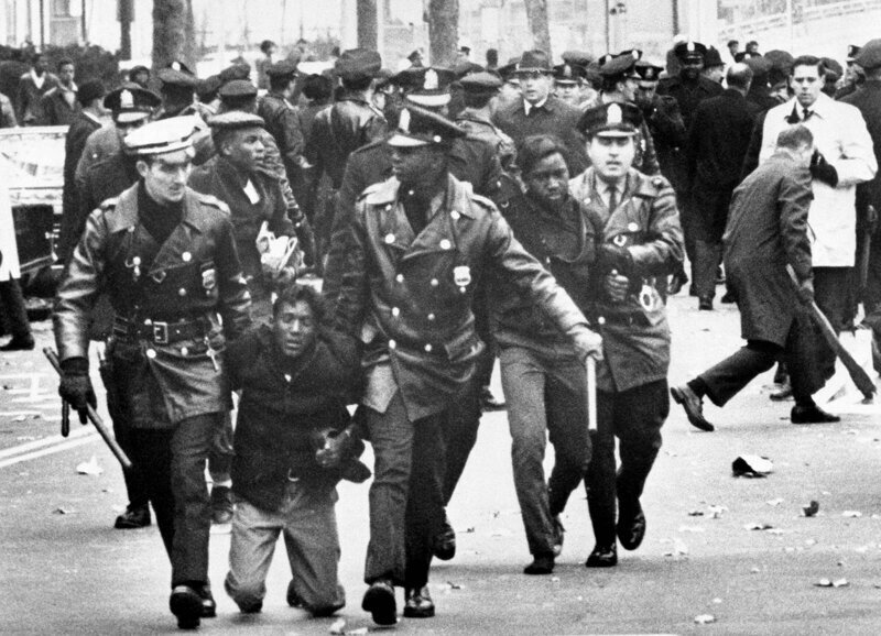 Полиция оттаскивает одного из демонстрантов, арестованных у здания администрации школы, где более 1000 протестующих вступили в потасовку с полицией, ноябрь 1967-го