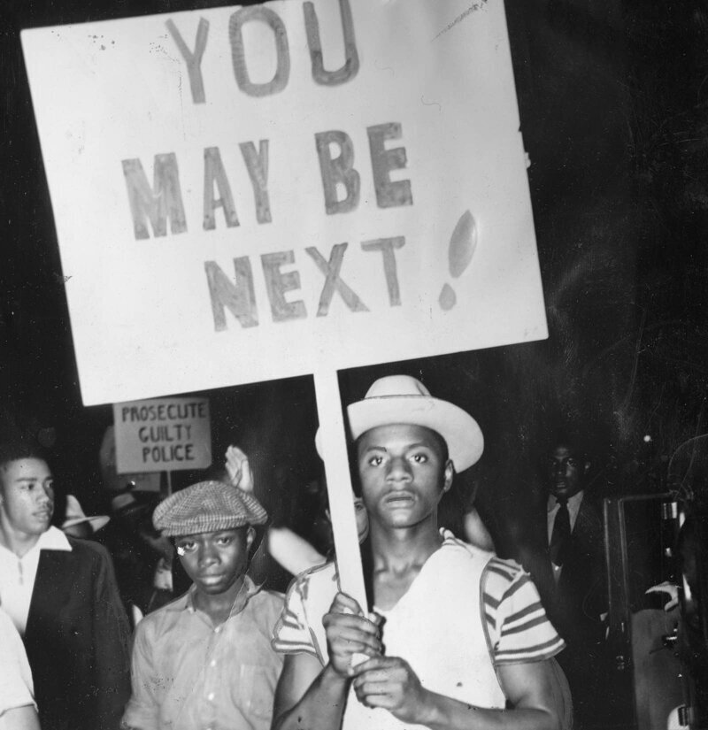 Протестующие держат плакаты и маршируют в знак протеста против жестокости полиции после расстрела чернокожего мужчины в Вашингтоне, округ Колумбия, 16 июля 1938 года