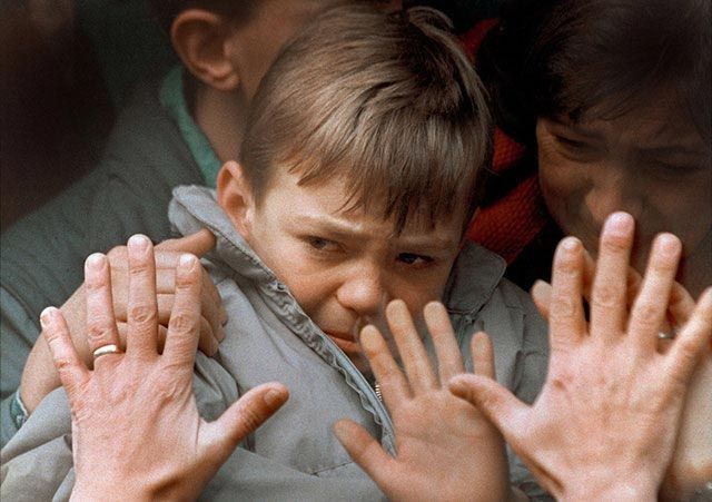 11. Отец прижал руки к окну автобуса, увозящего его жену и сына в безопасное место во время осады Сараево, 10 ноября 1992