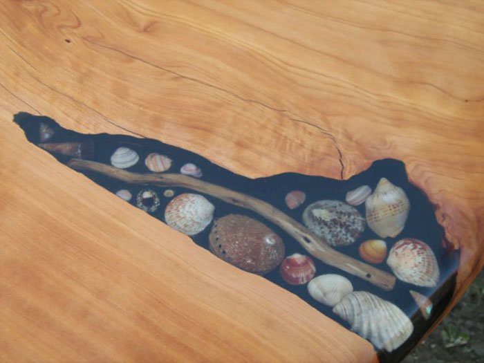 Художники заполняют трещины в столах ракушками, камешками и морскими звёздами 