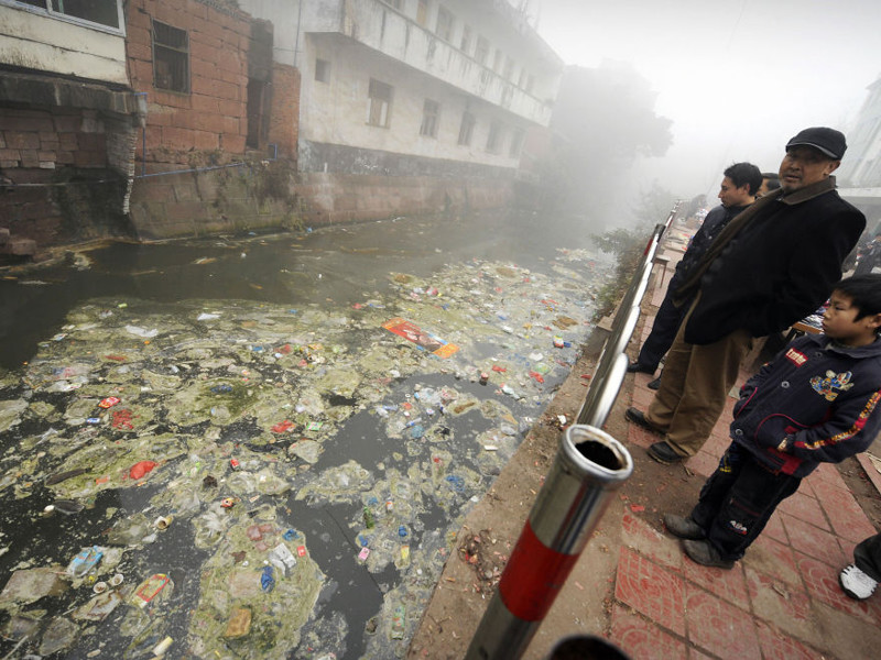 28. Жители Жугао, провинция Сычуань, смотрят на мусор в реке