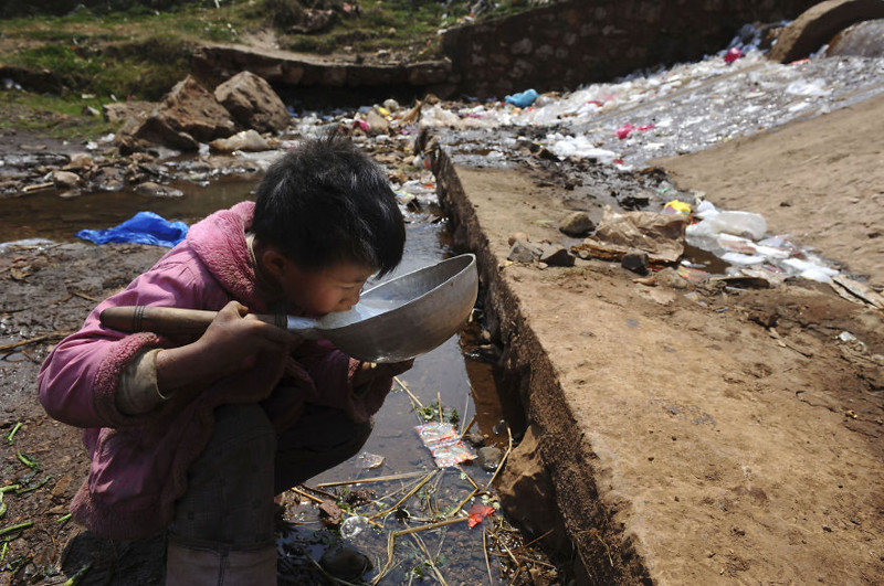 4. Ребёнок пьёт воду из загрязнённого ручья в уезде Фуюань провинции Юньнань