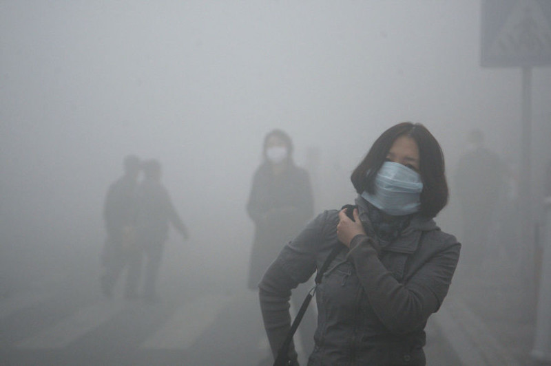 3. Девушка идёт сквозь смог в Пекине, где загрязнение мелкодисперсными частицами в 40 раз превышает безопасный уровень