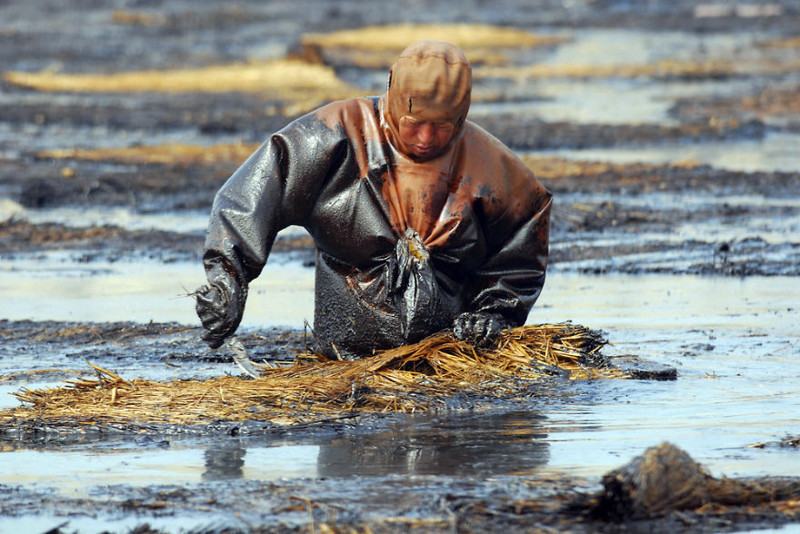 8. Рабочий пытается очистить воду от нефти, Далянь, Ляонин