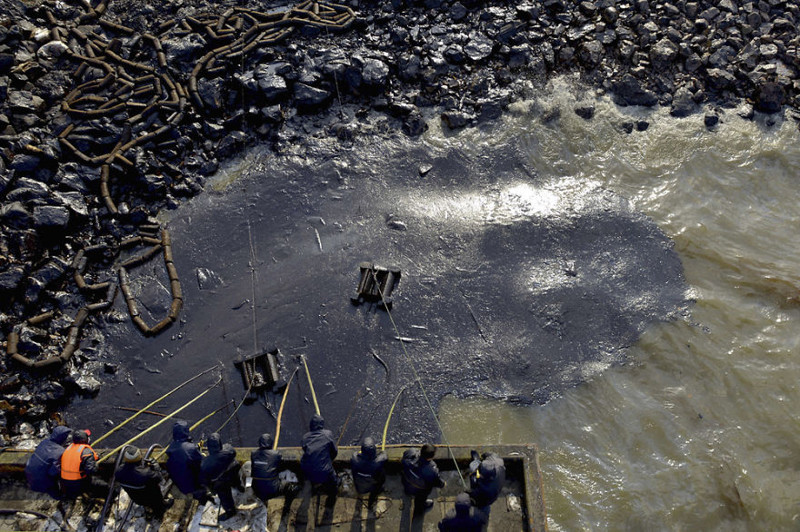 32. Рабочие собирают пролившуюся после взрыва на трубопроводе в Циндао, провинция Шаньдун