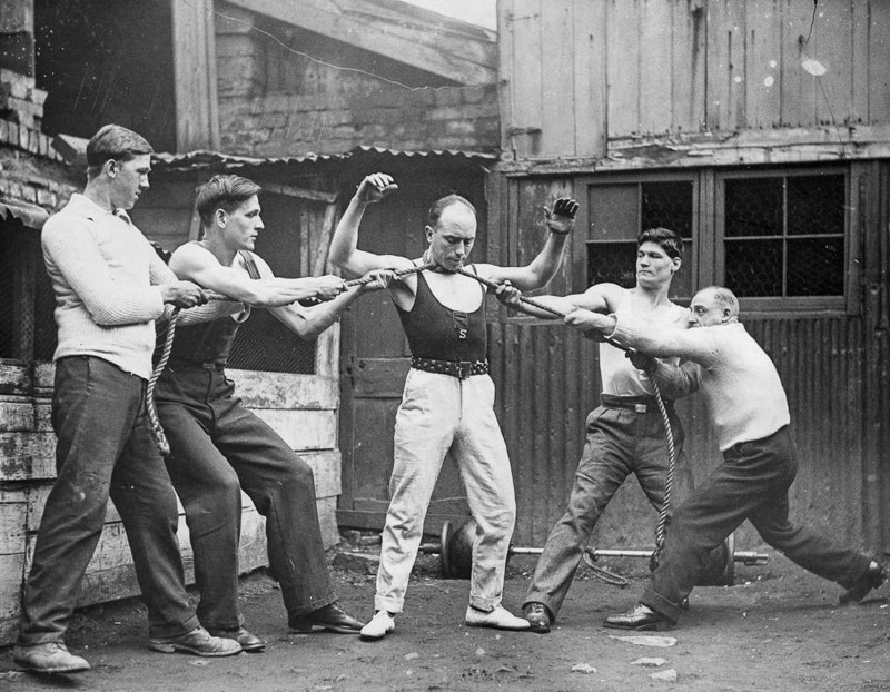 26 февраля 1932 года. Том Джойс, утверждавший, что является сильнейшим человеком в Бристоле, демонстрирует свою силу, когда четверо мужчин тянут веревку, обмотанную вокруг его шеи.  