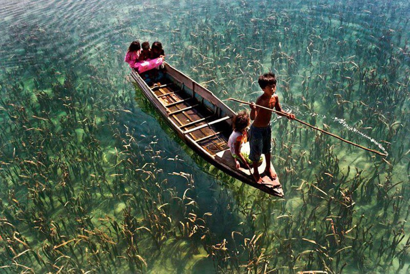 Дети катаются на лодке по кристально чистому озеру в Сабахе, Малайзия.