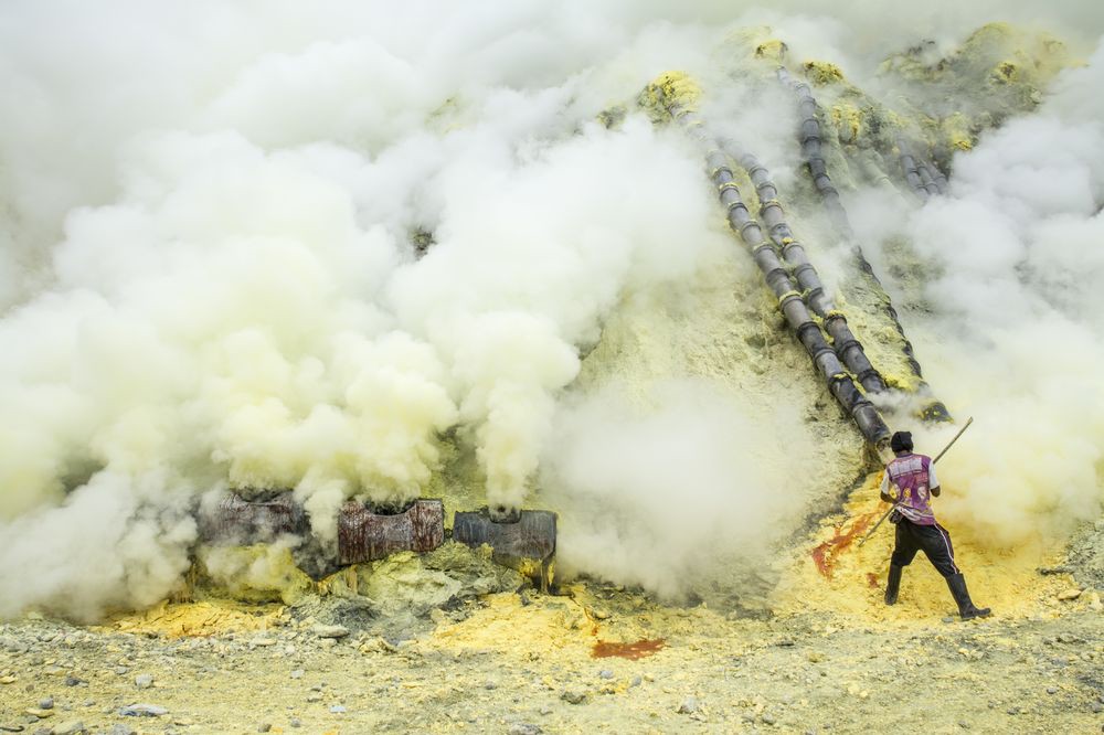 Рабочий собирает серу в кратере вулкана Иджен в Индонезии