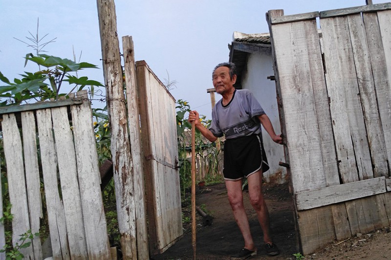 Пожилой мужчина выглядывает со своего двора в Туманганге