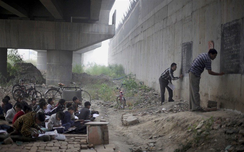 Два учителя-волонтера проводят бесплатные уроки для бедных детей в Нью-Дели, Индия.