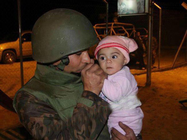 Иорданский солдат греет ручки сирийского ребенка, спасенного из страны, охваченной войной, 2013 год