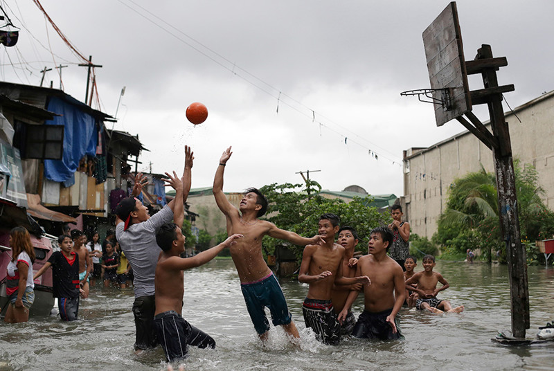 Филлипинские подростки играют в баскетбол на затопленной паводковыми водами площадке. Снимок сделан 8 июля, в предместье Манилы.