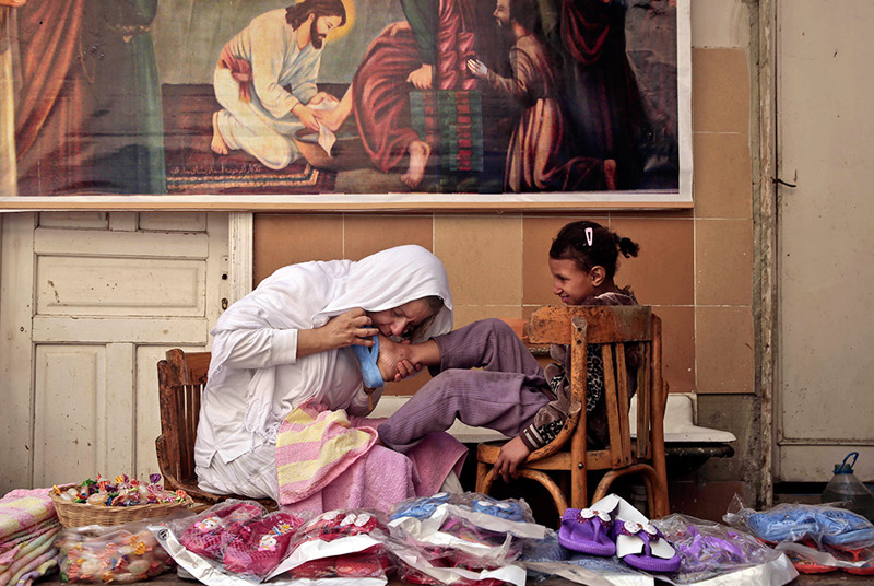 Мэгги Гобрэн, известная как мама Мэгги, целует ногу ребенка, которую только что отмыла от грязи. Фото сделано в окрестности Каира 25 февраля. Мама Мэгги основала организацию, помогающую бедным семьям. У организации 90 филиалов по всему миру.