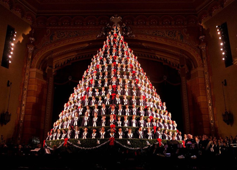 Певцы, которые стоят прямо в ёлке, репетируют рождественскую песню в городе Маскегон, США