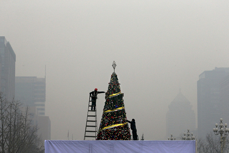 Рабочие украшают ель в дни смога в Пекине (Китай)