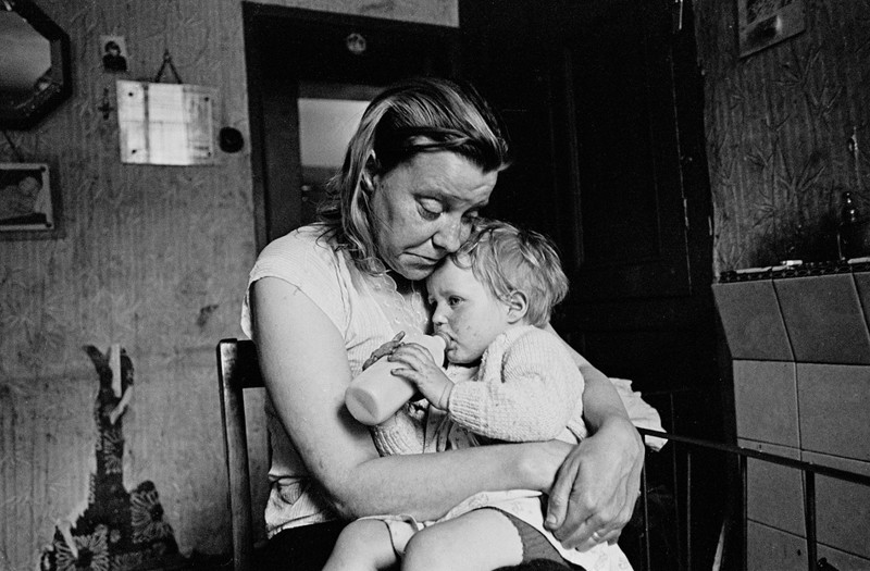 2. Шеффилд, май 1969. Миссис Тэнди обнимает младшего из пяти своих детей. Семья жила в разваливавшемся доме, принадлежавшем сталелитейному заводу. У нее не было газа, электричества, горячей воды, ванны. Она готовила пищу, разводя костер в гостиной.