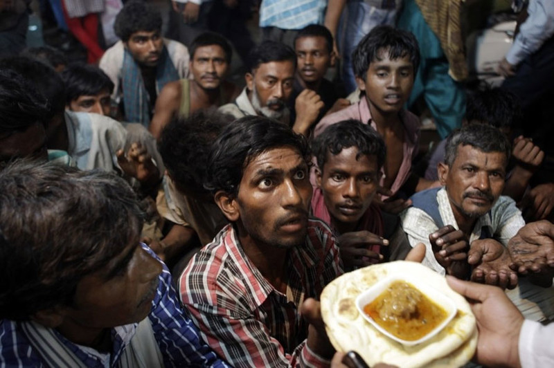 Индийские бездомные ждут, чтобы получить свою бесплатную порцию еды. Ее раздают возле мечети Ид аль-Фитр в Нью-Дели.