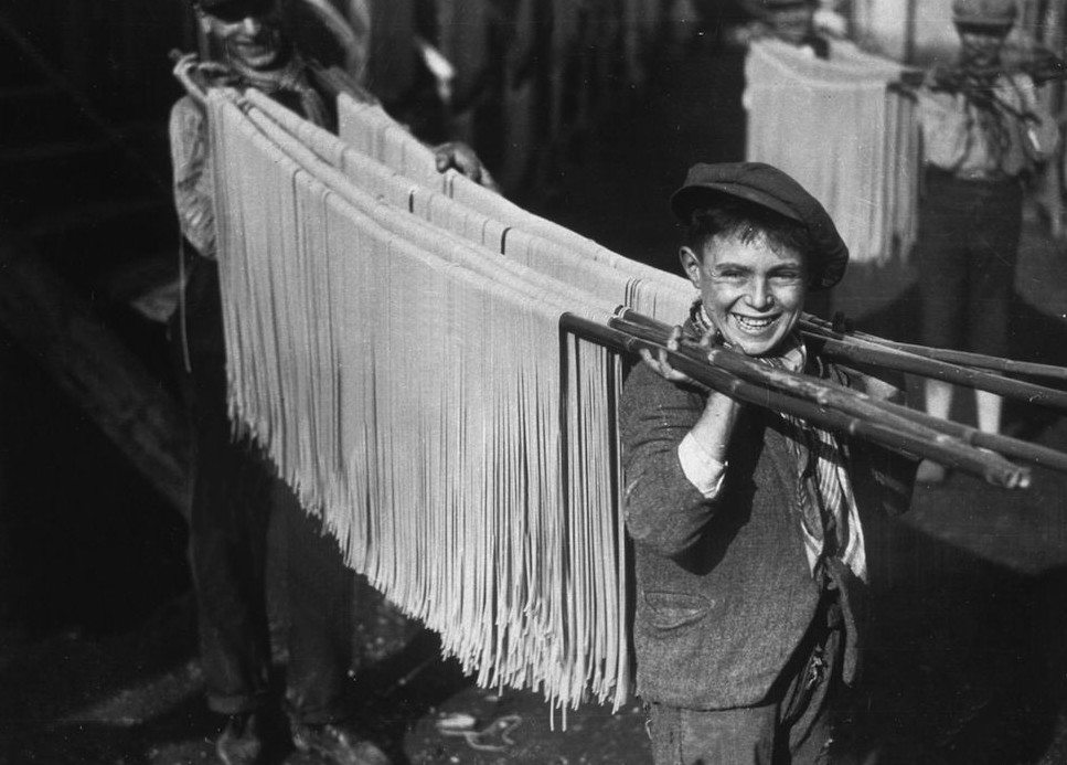 1. Молодые люди сушат на тростниковых шестах свежеприготовленную пасту на одной из макаронных фабрик Неаполя