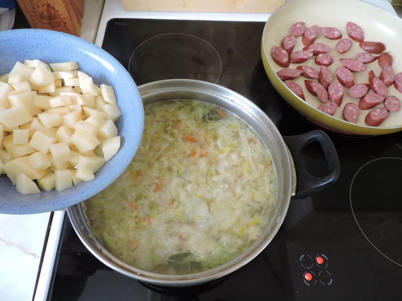 Картофель добавить в кастрюлю, а колбаски обжарить