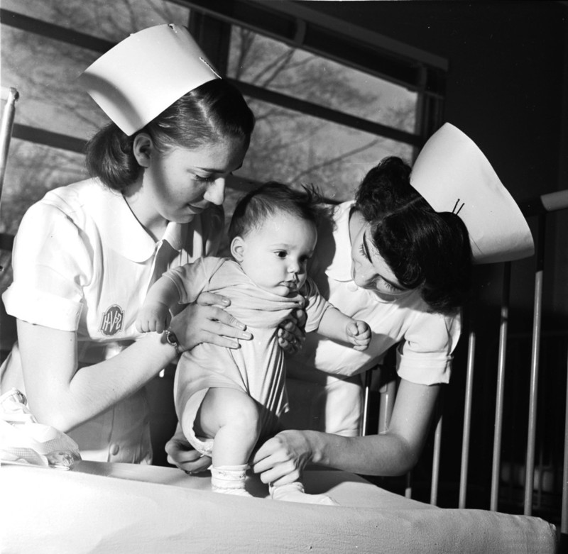 Медсестры помогают ребенку сделать несколько шажков (St Vincent’s Hospital, Монклер, Нью-Джерси, 1955 г.)