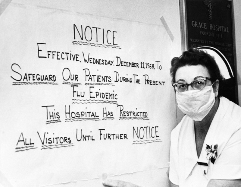 Медсестра Кливлендской больницы рядом с объявлением о том, что посещения запрещены из-за вспышки гриппа (1968 г.)