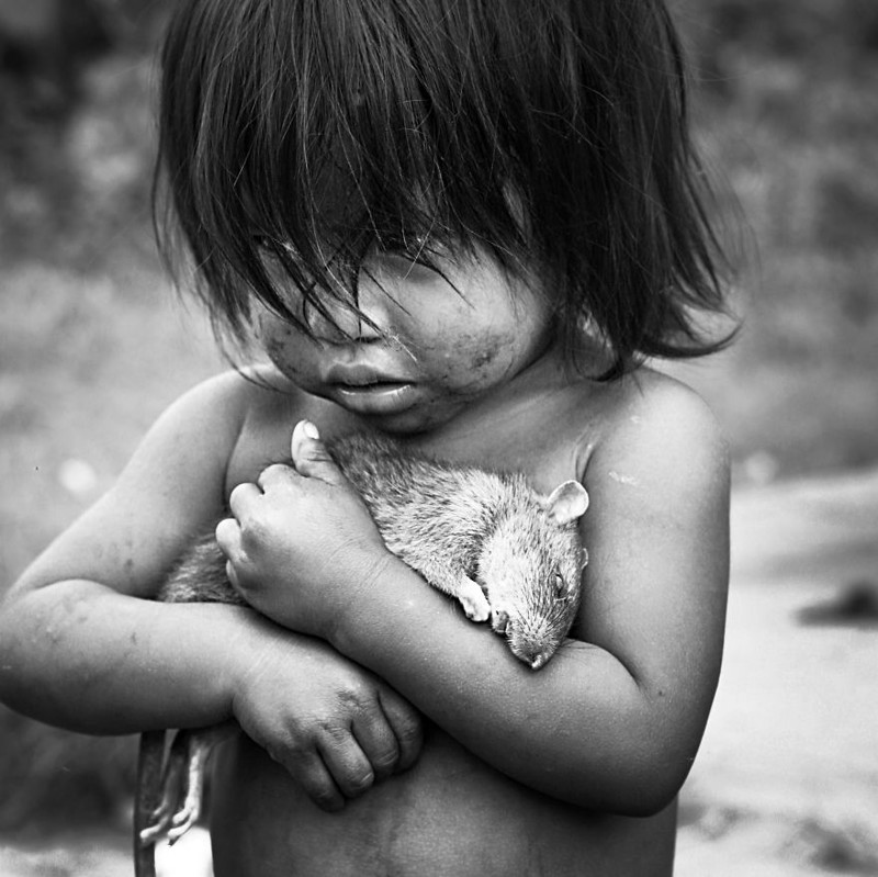 Индейская девочка крепко сжимает в руках тело мертвой крысы.