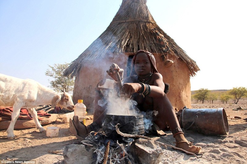 Молодая девушка из племени Химба готовит еду в живописной сельской местности Намибии