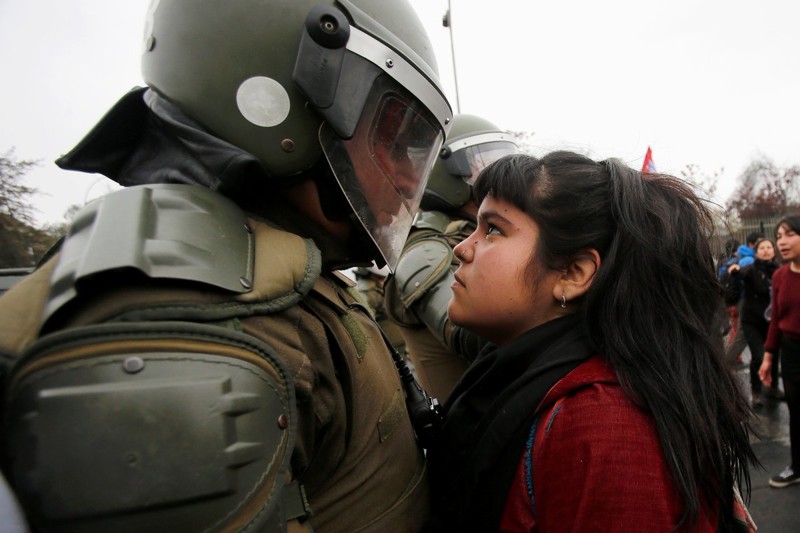 Демонстрантка и участник полицейского оцепления во время протестного митинга в Чили, сентябрь 2016 года.