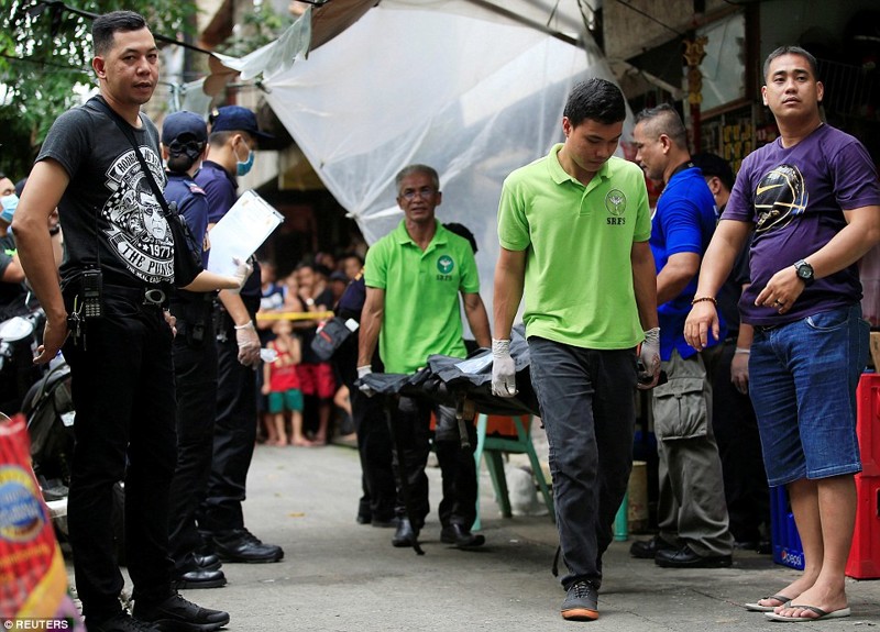 Представители власти несут мертвого человека, убитого во время "бойни против наркоманов" на Филиппинах