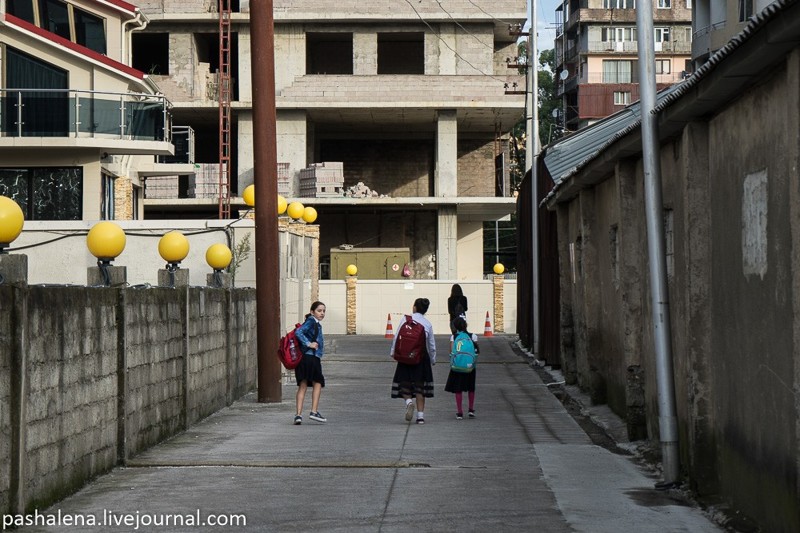 Дети идут в школу через переулок около стройки.