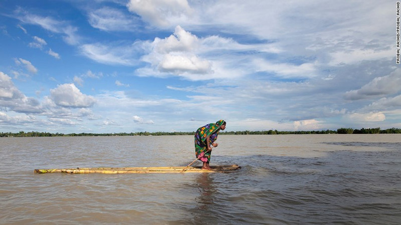 Пострадавшая от наводнения женщина на плоту приближается к лодке, ища сухое укрытие, Бангладеш.