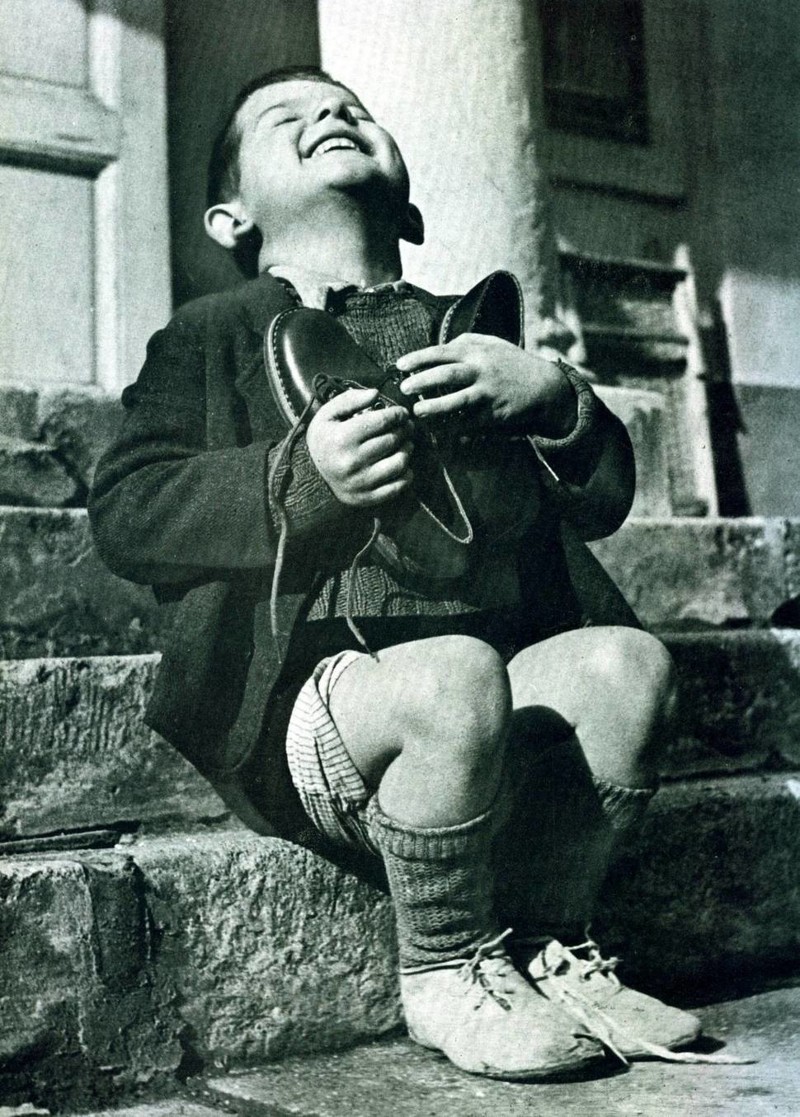 Верфель, 6-летний австрийский сирота, прижимает к груди новые ботинки, выданные ему Красным Крестом (1946 г.)