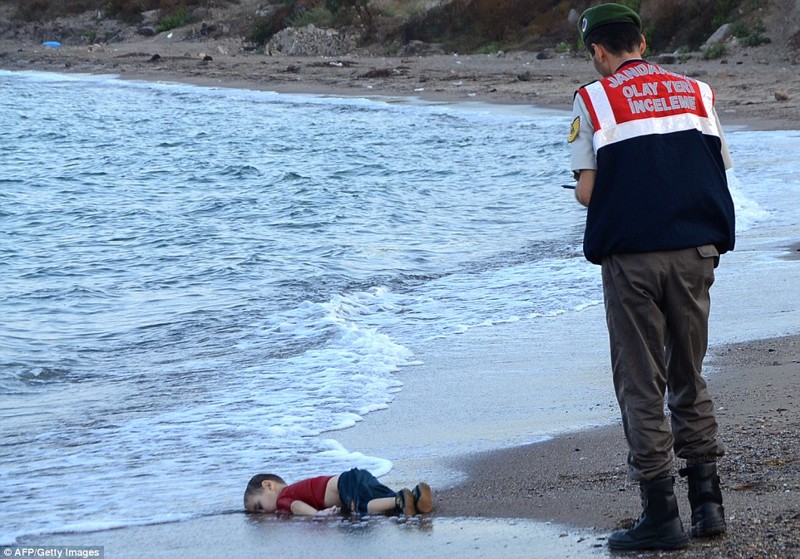 Смерть на пляже: Сотрудник турецкой полиции стоит рядом с телом ребенка-мигранта у берегов Бодрума, на юге Турции, 2 сентября 2015.