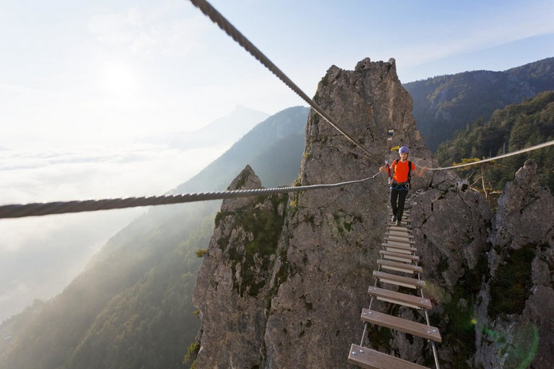 Молодая женщина пересекает верёвочный мост. Драконова стена, озеро Мондзее, Австрия. 