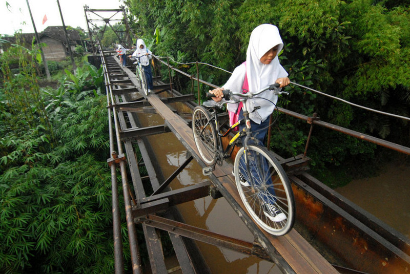Индонезийские дети идут в школу через подвесной мост, соединяющий две деревни в регионе Бойолали, Центральная Ява, Индонезия.