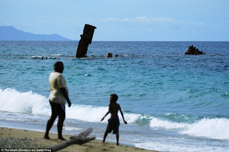 Местные жители играют и гуляют возле обломков транспортного корабля императорского флота Японии «Кинугава Мару» на пляже Тассафаронга острова Гуадалканал, Соломоновы острова