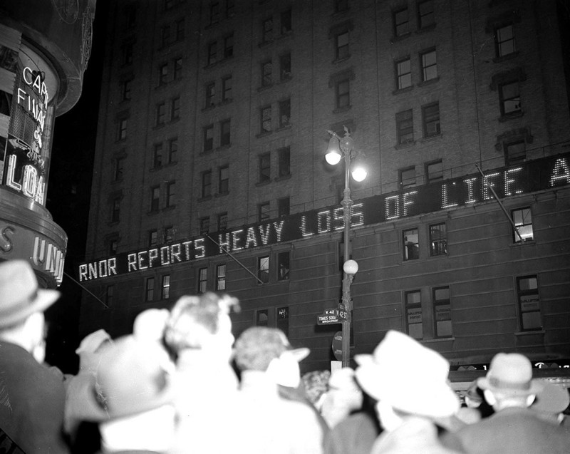 Толпа читает новости на электронном табло на Нью-Йорк-Таймс-билдинг в Нью-Йорке, 7 декабря 1941 года