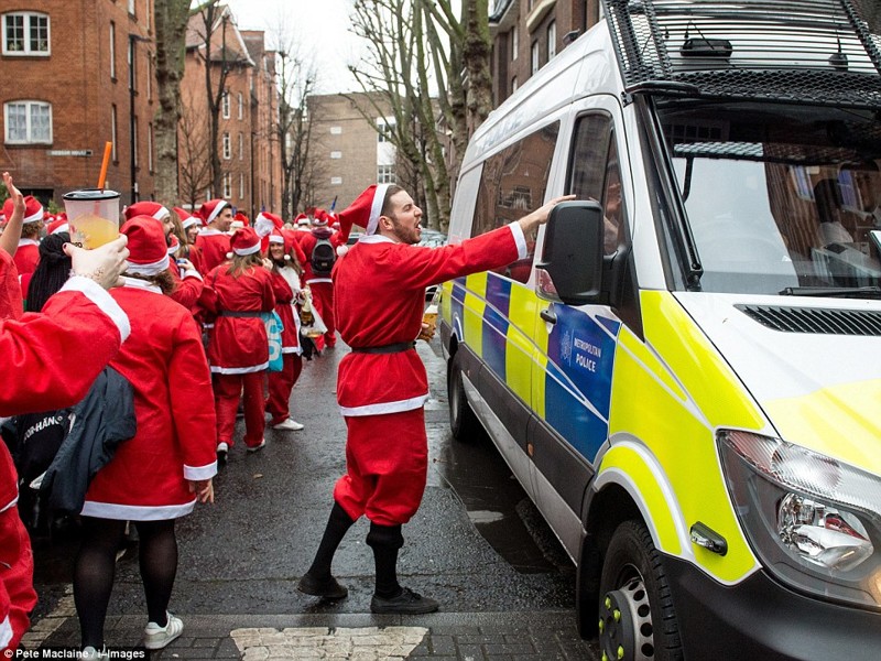 Вернемся в Лондон: сердитый Санта жестикулирует и кричит на полицейских, попивая пиво во время марша Santacon в Лондоне