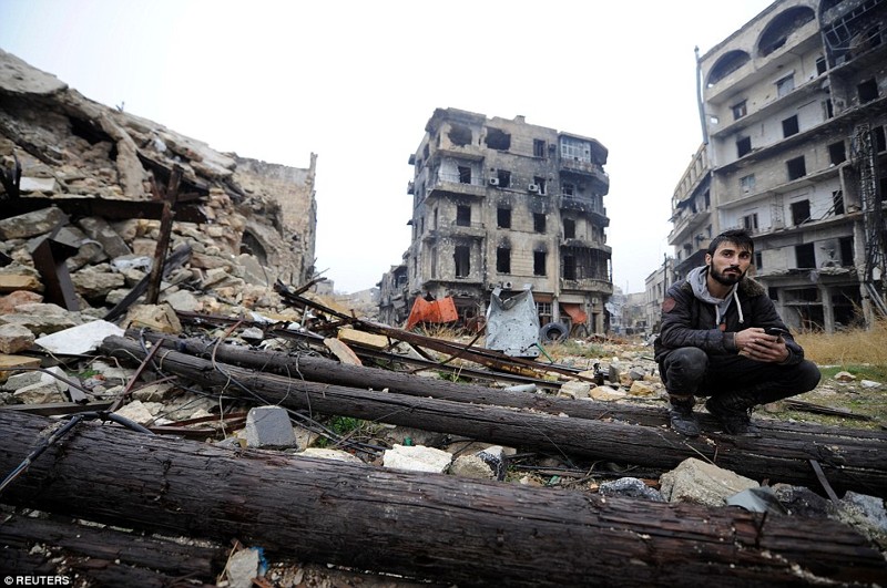 Человек сидит среди мусора возле мечети Омейядов, в контролируемой правительством области Алеппо, во время пресс-тура, Сирия