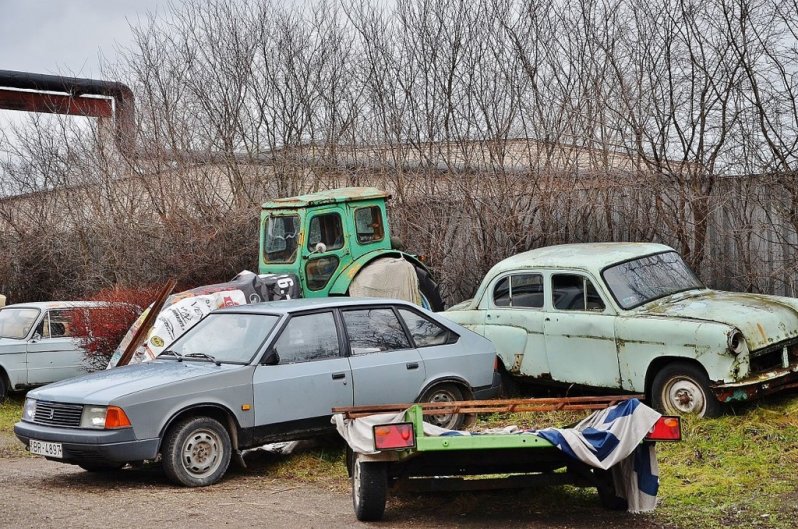 Вокруг склада залежи старых советских авто, ржавеющих под дождем и снегом.