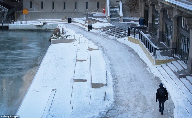 Пешеход идет по частично замерзшей реке Чикаго при минусовой температуре в понедельник утром