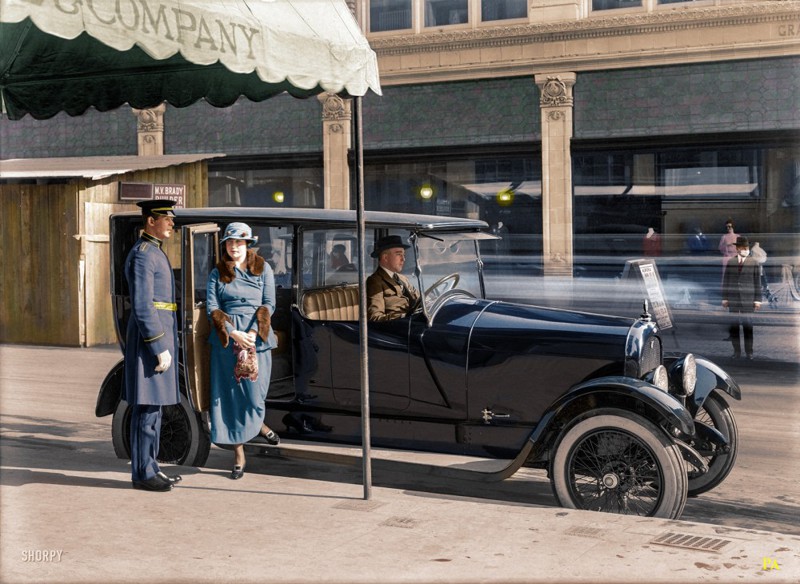 Дормен открывает дверь даме выходящей из автомобиля марки Marmon. На другой стороне улицы можно заметить джентльмена в медицинской маске. Сан-Франциско, 1919 год. 