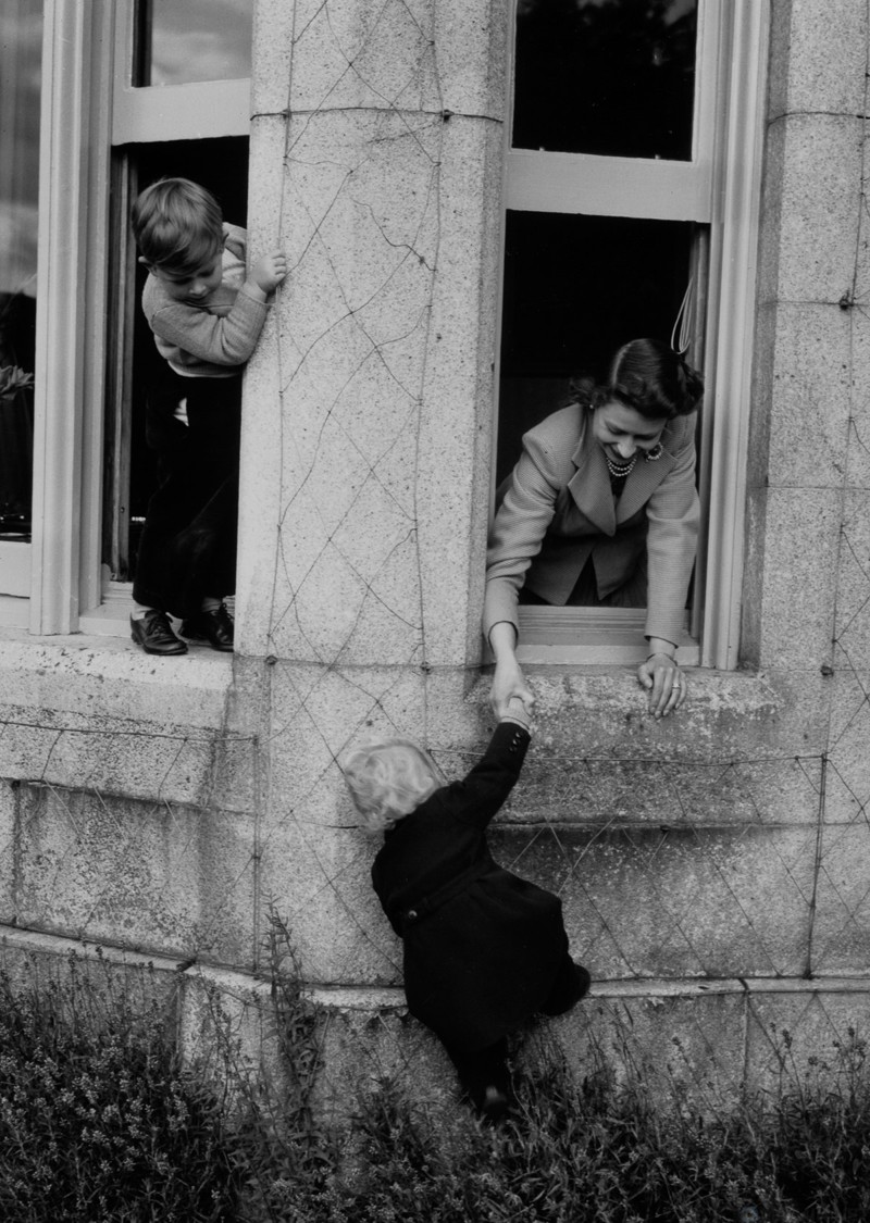 28 сентября 1952: Королева Елизавета затаскивает маленького принца Чарльза в окно