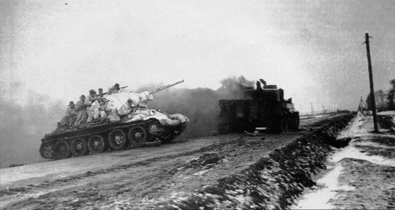 14. Cоветский танк Т-34 с десантом пересекает магистраль Житомир-Бердичев. На дороге выгорает танк Pz.Kpfw. VI «Тигр». 1-й Украинский фронт, январь 1944-го года