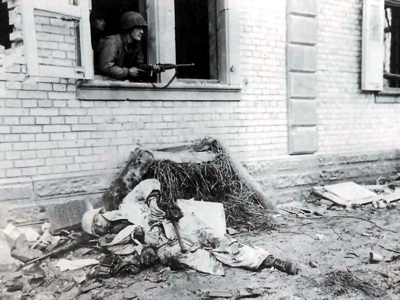 71. Американский пехотинец позирует рядом с телом убитого немецкого солдата