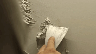 Рабочий украшает гипсокартоновые стены объемными картинами, используя лишь шпатлевку
